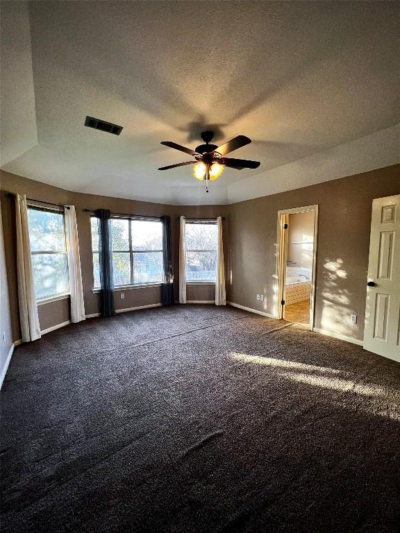 unfurnished room with visible vents, baseboards, a ceiling fan, and dark carpet