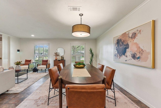 dining space with a wealth of natural light, visible vents, baseboards, and ornamental molding