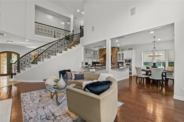 living area with stairs, visible vents, a towering ceiling, and dark wood-type flooring