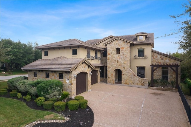 mediterranean / spanish-style home with a balcony, driveway, a garage, stucco siding, and stone siding
