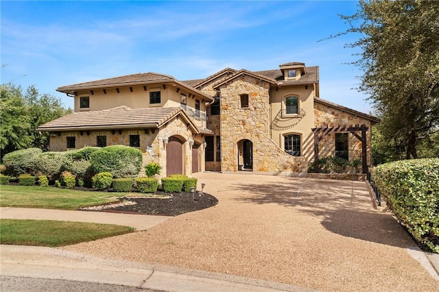 mediterranean / spanish home featuring stone siding, stucco siding, and curved driveway