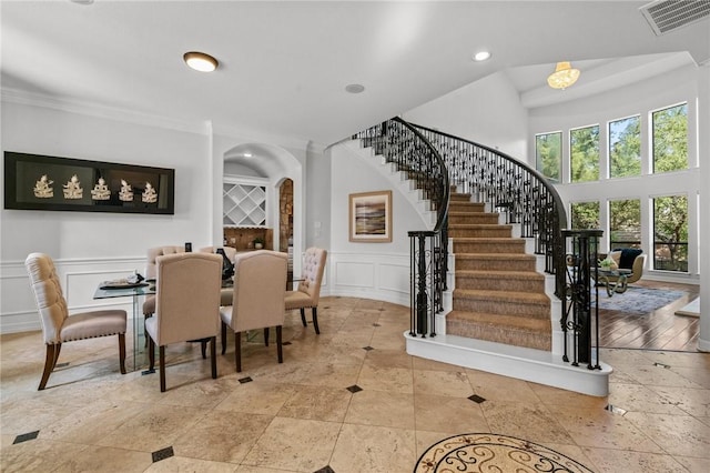 dining space with stairs, a decorative wall, visible vents, recessed lighting, and crown molding