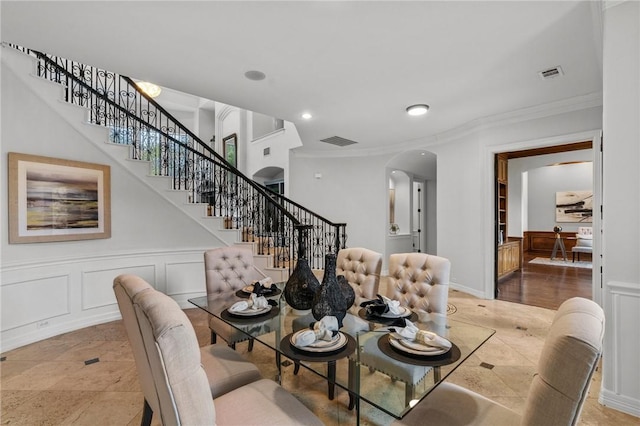 dining area with crown molding, visible vents, arched walkways, and stairway