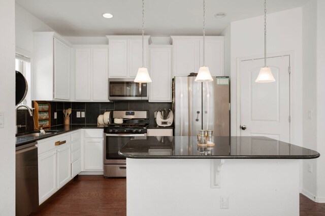 800 Totis Rd, Austin, TX 78748 - kitchen with appliances with stainless steel finishes, dark countertops, a kitchen island, tasteful backsplash, and white cabinets