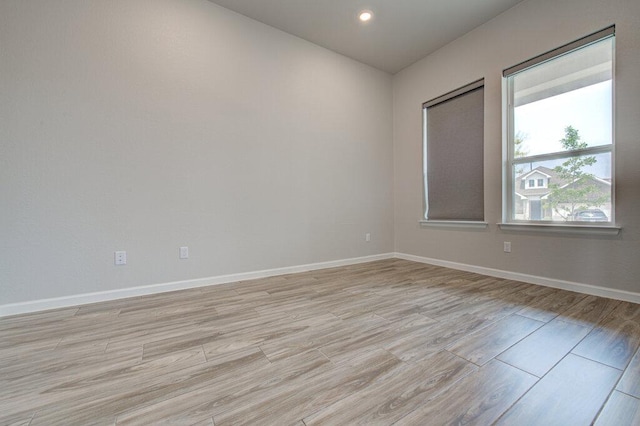 empty room with recessed lighting, baseboards, and light wood-style floors
