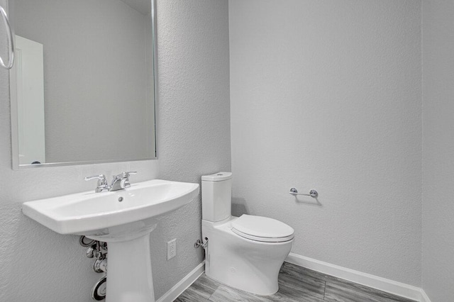 114 Joseph Hawkins Ln, Bastrop, TX 78602 - bathroom featuring toilet, wood finished floors, baseboards, a sink, and a textured wall