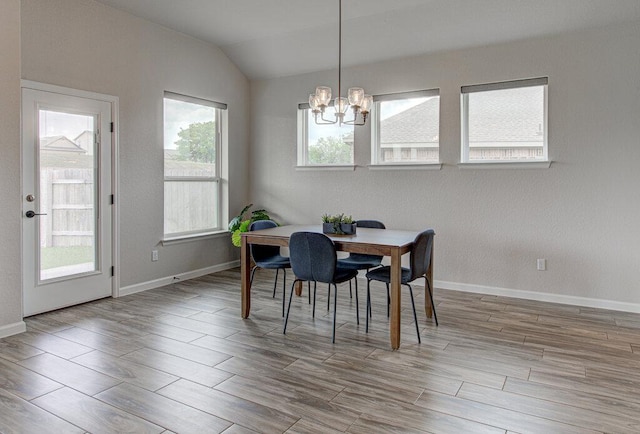 dining space featuring lofted ceiling, a notable chandelier, baseboards, and wood finished floors