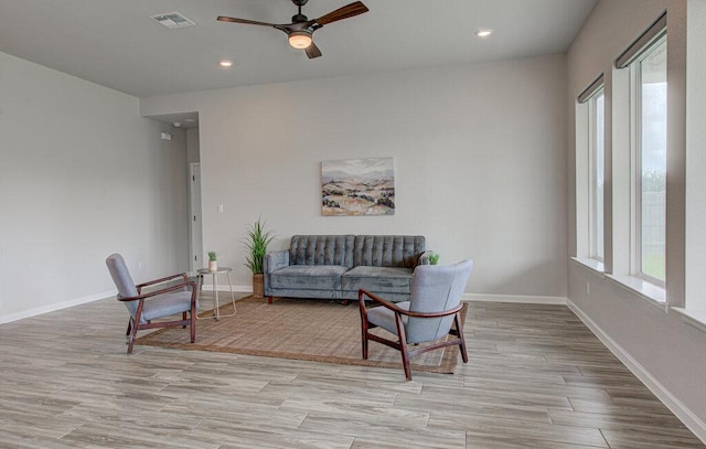 living area featuring a ceiling fan, baseboards, visible vents, and wood finished floors