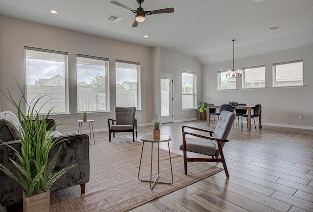 living area featuring baseboards, wood finished floors, visible vents, and ceiling fan with notable chandelier