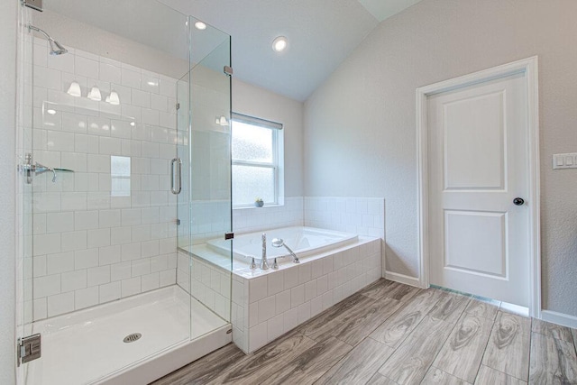 bathroom featuring a garden tub, wood finished floors, a stall shower, baseboards, and lofted ceiling