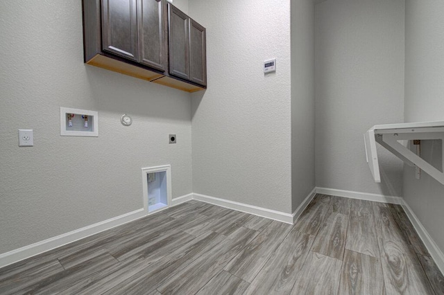laundry area with gas dryer hookup, hookup for a washing machine, wood finished floors, hookup for an electric dryer, and cabinet space