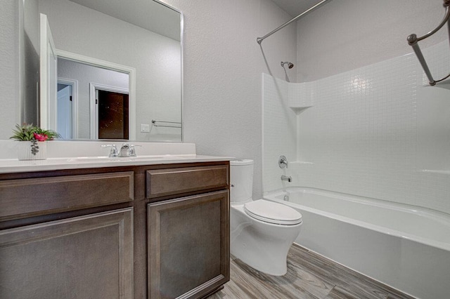 full bathroom featuring toilet, wood finished floors, vanity, and washtub / shower combination