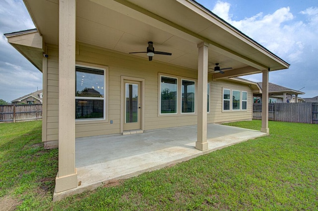 back of house featuring a fenced backyard, a ceiling fan, and a yard