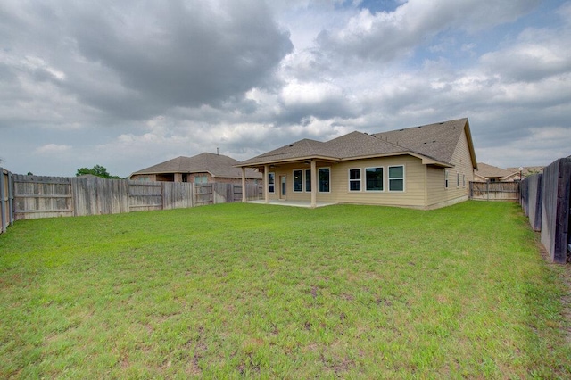 rear view of house with a patio, a lawn, and a fenced backyard