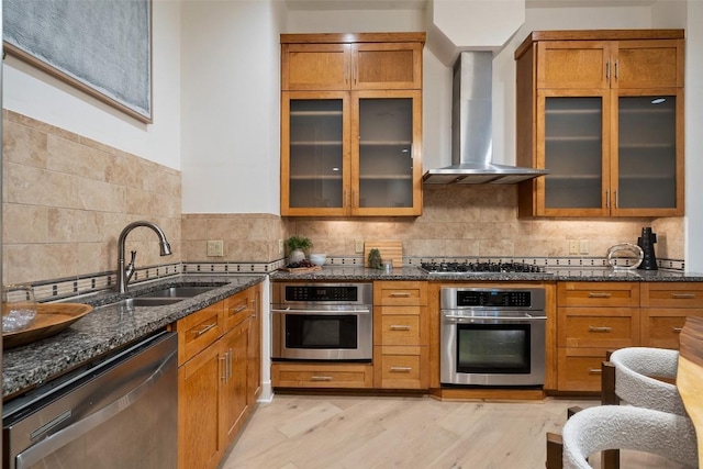 3007 Windsor Rd Unit B, Austin, TX 78703 - kitchen with appliances with stainless steel finishes, wall chimney range hood, a sink, dark stone counters, and brown cabinetry