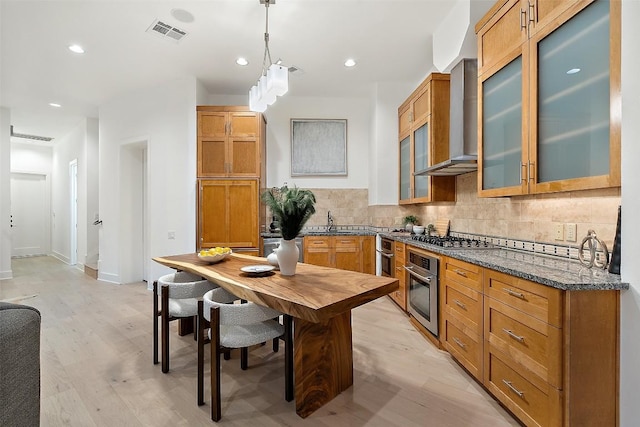 3007 Windsor Rd Unit B, Austin, TX 78703 - kitchen featuring wall chimney range hood, appliances with stainless steel finishes, light wood-style floors, a sink, and decorative backsplash