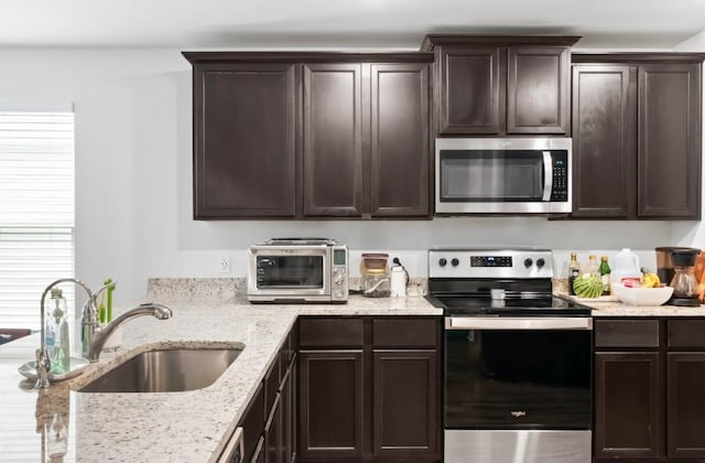 18720 Speculator Ln, Elgin, TX 78621 - kitchen featuring light stone counters, stainless steel appliances, a sink, and dark brown cabinetry