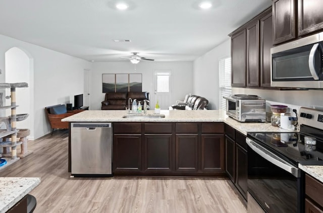 18720 Speculator Ln, Elgin, TX 78621 - kitchen with a peninsula, a sink, stainless steel appliances, dark brown cabinetry, and arched walkways