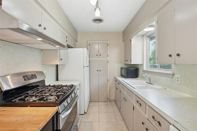 7000 Miranda Dr, Austin, TX 78752 - kitchen featuring gas stove, under cabinet range hood, backsplash, black microwave, and freestanding refrigerator