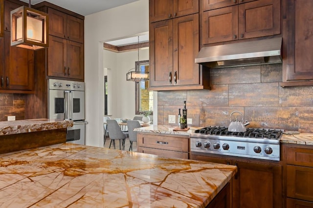 21216 Bertram Ln, Spicewood, TX 78669 - kitchen with appliances with stainless steel finishes, under cabinet range hood, light countertops, and decorative backsplash