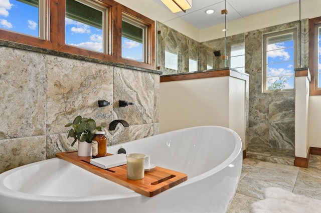 21216 Bertram Ln, Spicewood, TX 78669 - bathroom featuring a walk in shower, a soaking tub, tile walls, and recessed lighting