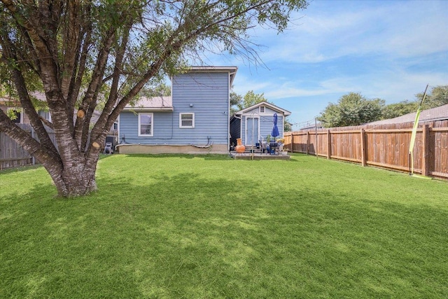 back of house with a lawn and a fenced backyard