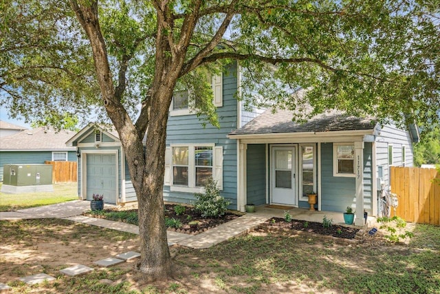 view of front of house featuring covered porch, a shingled roof, a garage, and fence