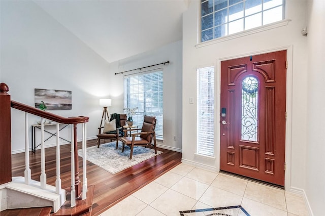 entryway featuring stairs, baseboards, and high vaulted ceiling
