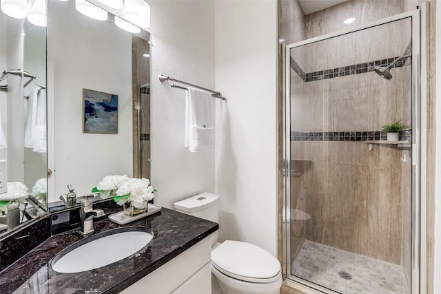 full bathroom with a stall shower, vanity, and toilet