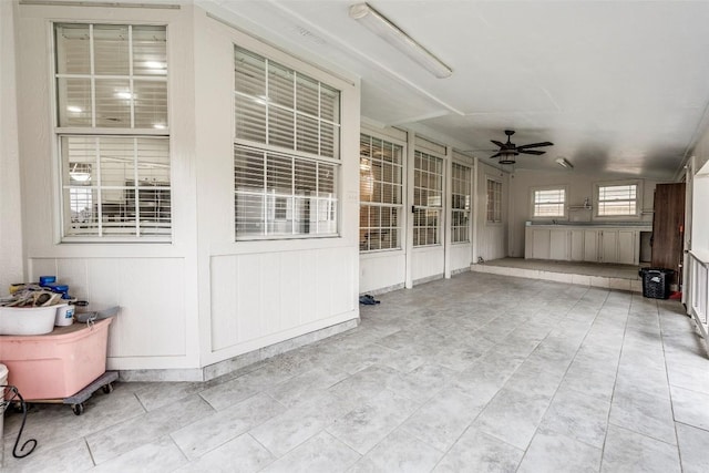 unfurnished sunroom featuring ceiling fan