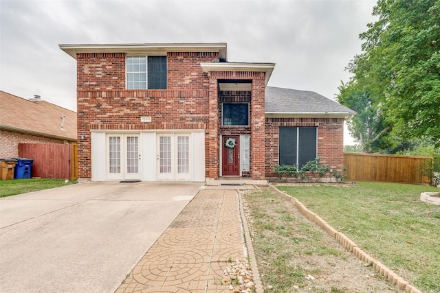 view of front of house featuring a front yard, brick siding, french doors, and fence