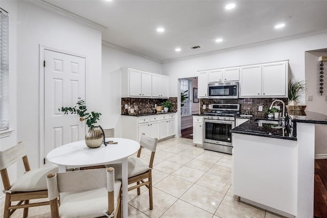 kitchen featuring a sink, a peninsula, crown molding, tasteful backsplash, and appliances with stainless steel finishes