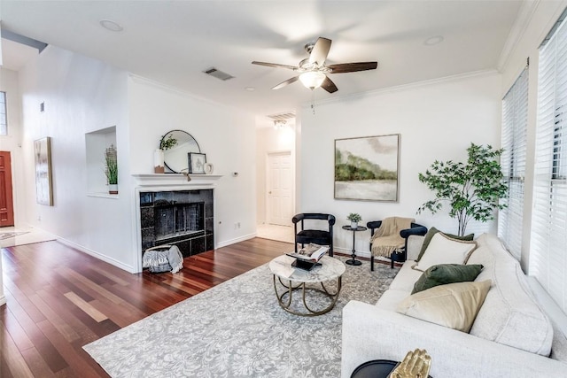 living area with a wealth of natural light, visible vents, wood finished floors, and a ceiling fan