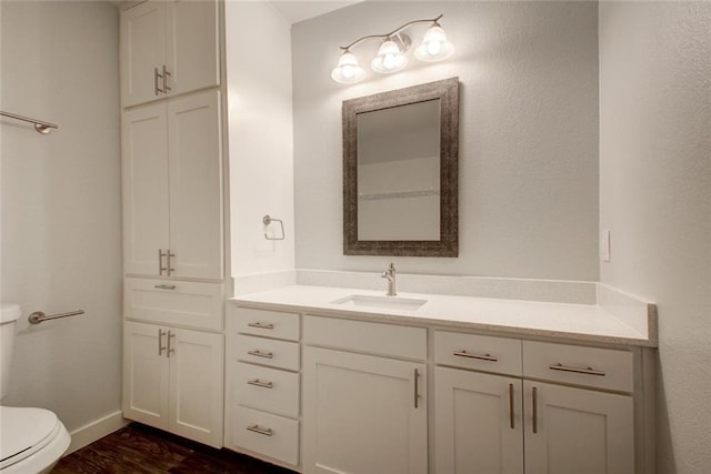 bathroom featuring vanity, toilet, baseboards, and wood finished floors