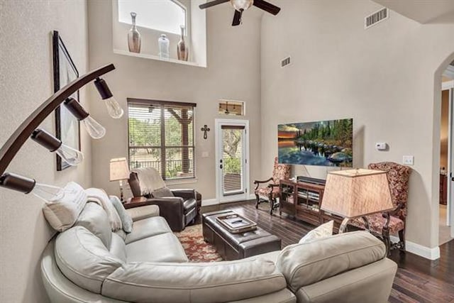 living area with wood finished floors, visible vents, baseboards, ceiling fan, and arched walkways