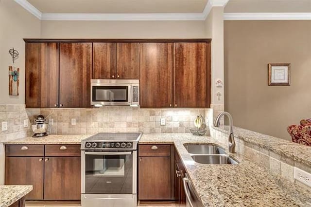 kitchen with a sink, stainless steel appliances, ornamental molding, backsplash, and light stone countertops