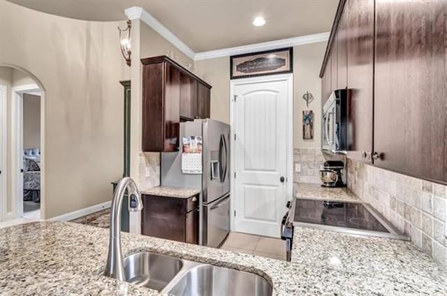 kitchen featuring a sink, stainless steel appliances, ornamental molding, decorative backsplash, and dark brown cabinets