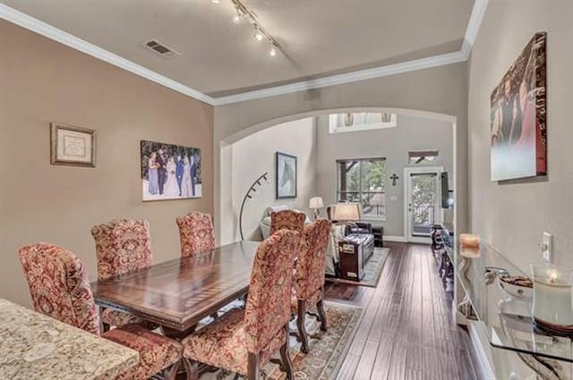 dining area with hardwood / wood-style floors, ornamental molding, track lighting, visible vents, and arched walkways