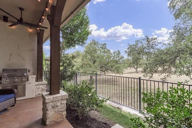 exterior space featuring a ceiling fan, an outdoor kitchen, and fence