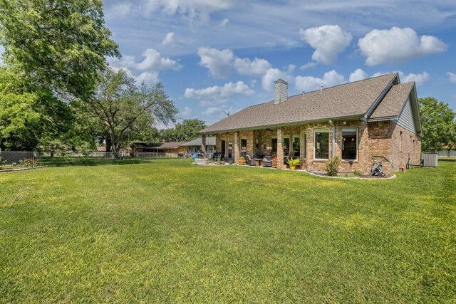 1338 Donovan St, Gonzales, TX 78629 - rear view of house featuring a chimney, a lawn, central air condition unit, brick siding, and roof with shingles