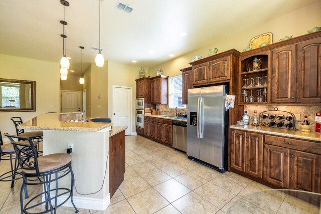 1338 Donovan St, Gonzales, TX 78629 - kitchen with a kitchen bar, a sink, stainless steel appliances, visible vents, and tasteful backsplash