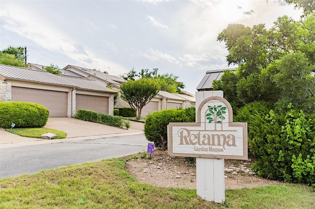 community sign with driveway and a garage