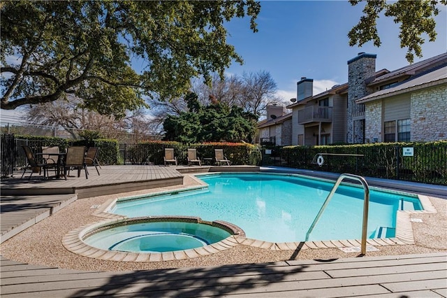 view of pool featuring a pool with connected hot tub, fence, and a wooden deck