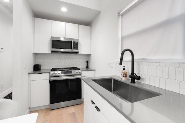 400 E 30th St Unit 200, Austin, TX 78705 - kitchen with appliances with stainless steel finishes, a sink, decorative backsplash, white cabinetry, and recessed lighting