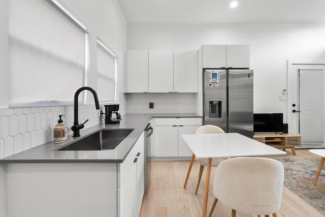 400 E 30th St Unit 200, Austin, TX 78705 - kitchen with a sink, stainless steel appliances, decorative backsplash, light wood-type flooring, and white cabinets