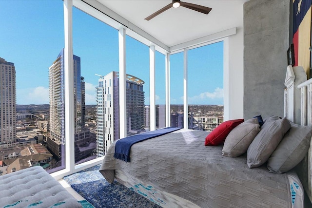 bedroom featuring a city view, a wall of windows, and a ceiling fan