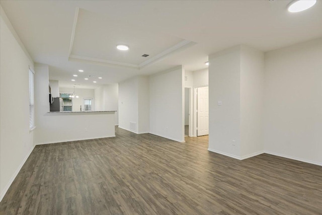 201 Cascata Way, Liberty Hill, TX 78642 - unfurnished living room with dark wood finished floors, a raised ceiling, baseboards, recessed lighting, and ornamental molding