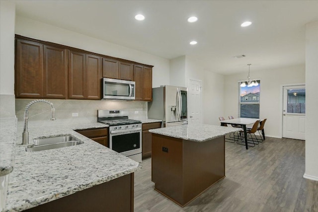201 Cascata Way, Liberty Hill, TX 78642 - kitchen with stainless steel appliances, a sink, decorative backsplash, a center island, and wood finished floors