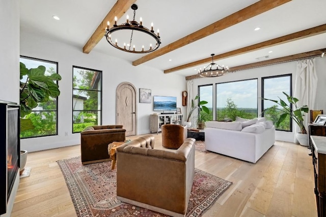 living area featuring an inviting chandelier, a healthy amount of sunlight, and beam ceiling