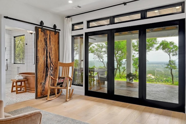 doorway to outside featuring recessed lighting, visible vents, a barn door, and wood finished floors